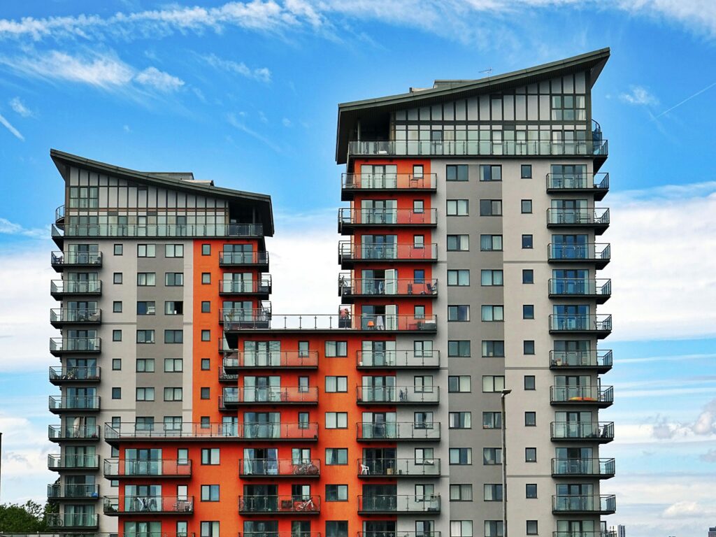 Modern high-rise apartment buildings with unique architecture under a vibrant blue sky.